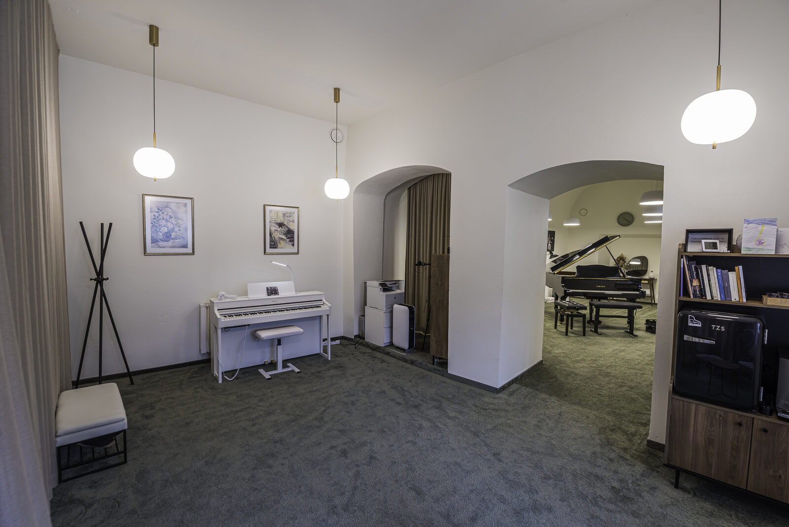 The studio's practice room, with a digital piano in the foreground and the grand piano visible through the archway