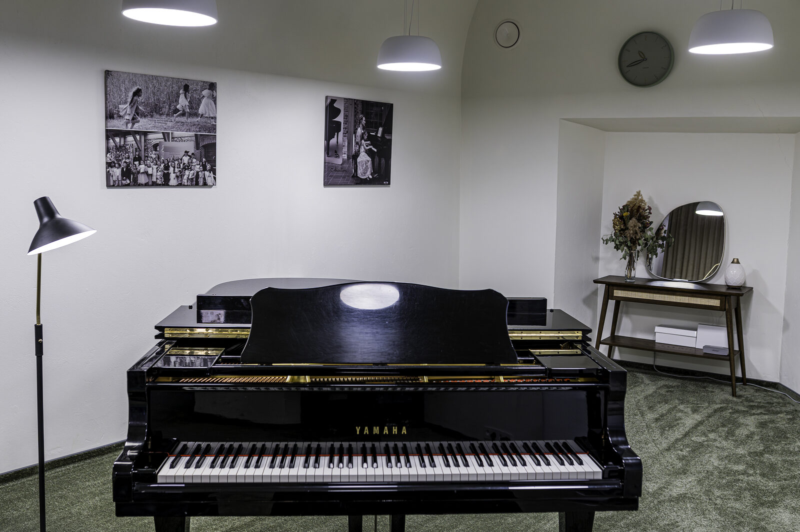 The studio's grand piano, with framed photos of past student performances on the wall behind it